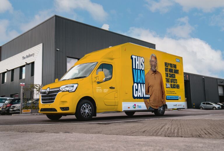 Photo of a yellow van parked outside a warehouse. On the van is the text "This Van Can" with a photo of an older black male, the NHS logo and the text "Help you find out more about the cancer that affects 1 in 4 black men".